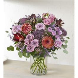 Mixed bouquet of lavender and pink flowers in a clear glass vase