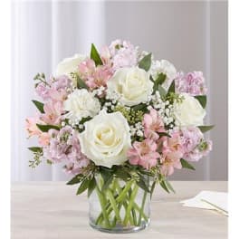 White roses and pink flowers in a clear glass vase