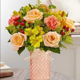 Peach roses and yellow flowers in a pink textured vase