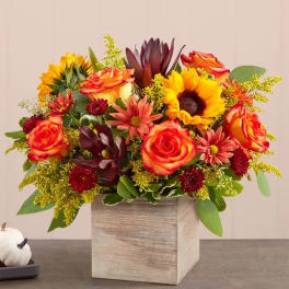 Mixed bouquet of orange roses and sunflowers in a wooden box