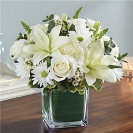 White lilies and roses arranged in a square glass vase