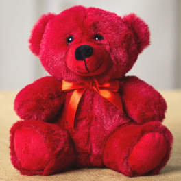 Red teddy bear with an orange ribbon bow