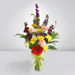 Mixed bouquet in a glass vase with red, yellow, pink, and purple flowers