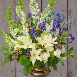 White lilies and roses with purple and blue flowers in a gold vase