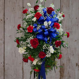 Standing floral spray with red roses, carnations, and blue ribbon
