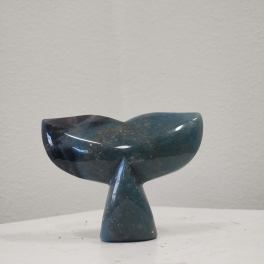 Dark blue whale tail sculpture on a white surface
