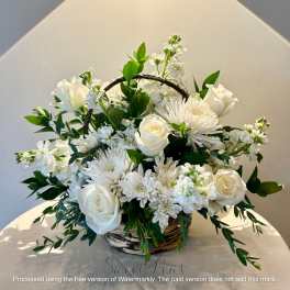 White roses and chrysanthemums in a wicker basket with greenery