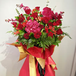 Large bouquet of red and pink flowers wrapped in red and gold paper