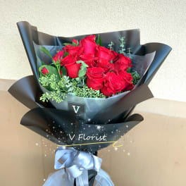 Bouquet of red roses wrapped in black paper with a silver ribbon