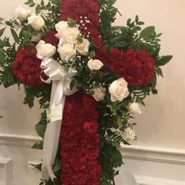 Red and white floral cross on an easel with a white ribbon