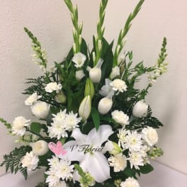 Tall white floral arrangement with lilies, carnations, and other blooms in a fan shape