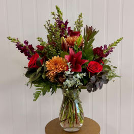 Mixed bouquet of red and orange flowers in a clear glass vase