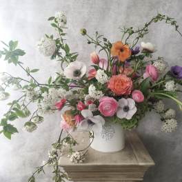 Mixed bouquet in a white vase with pink, orange, purple, and white blooms