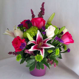 Pink and white roses with a lily in a purple vase