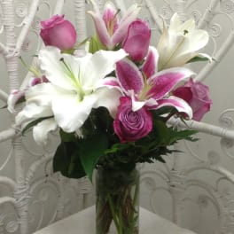 Pink and white lilies with roses in a clear glass vase
