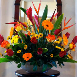 Tropical bouquet with orange and red flowers in a bowl vase