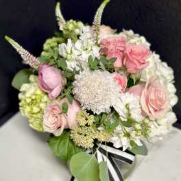 Pink and white bouquet with roses and hydrangeas tied with a striped ribbon