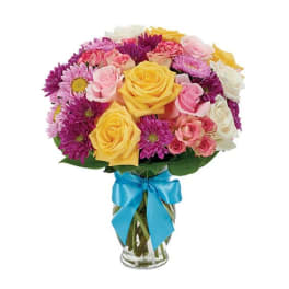 Mixed bouquet of yellow and pink roses with purple daisies in a glass vase