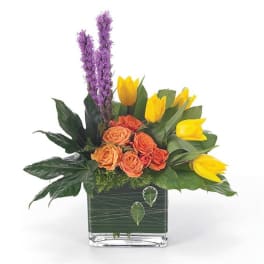 Orange roses and yellow tulips in a square glass vase