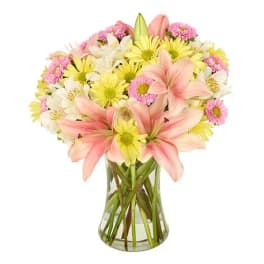 Pink lilies and yellow daisies in a clear glass vase