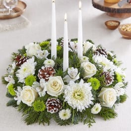 White floral candle centerpiece with pinecones and three taper candles