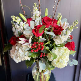 Red roses and white flowers arranged in a clear glass vase