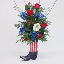 Red roses and blue-white flowers arranged in a cowboy boot vase