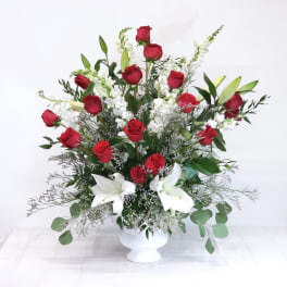 Red roses and white lilies in a white pedestal vase