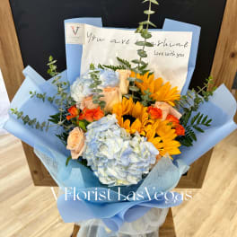 Blue and peach bouquet with hydrangeas, roses, and sunflowers