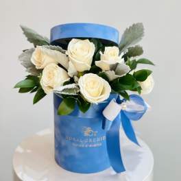White roses arranged in a blue gift box with a ribbon