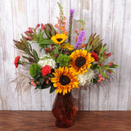 Mixed bouquet with sunflowers, red blooms, and white flowers in a red vase