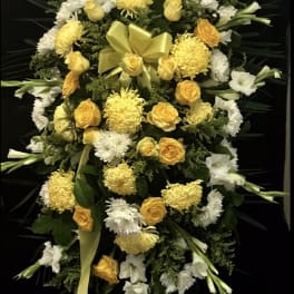 Yellow and white floral standing spray with a ribbon bow