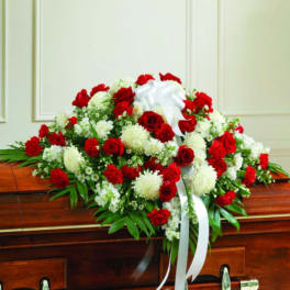 Red and white floral casket spray with a white ribbon