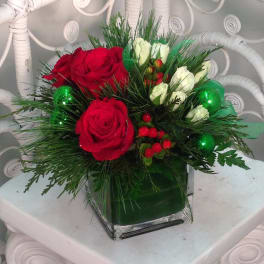Red and white rose arrangement in a square glass vase with green accents