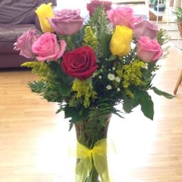 Bouquet of pink, red, and yellow roses in a clear glass vase