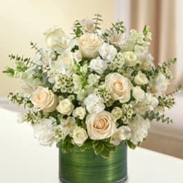 Cream roses and white flowers arranged in a green vase