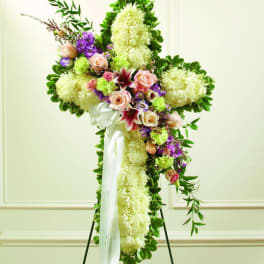 Standing floral cross with white and purple flowers and a white ribbon