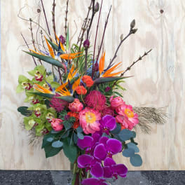 Tall tropical bouquet with orchids, bird of paradise, and pink blooms in a glass vase
