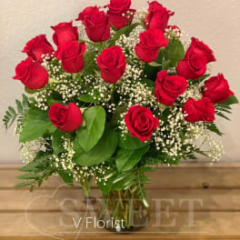 Bouquet of red roses with white baby's breath in a clear glass vase