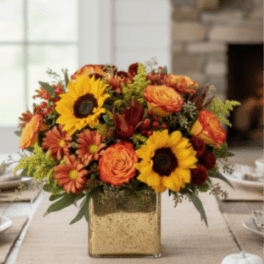 Autumn centerpiece with sunflowers, orange roses, and mums in a square gold vase
