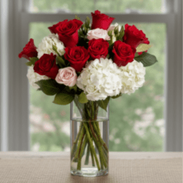 Red roses and white hydrangeas in a clear glass vase