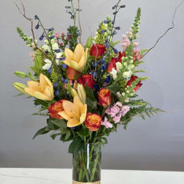 Mixed bouquet of lilies, roses, and snapdragons in a glass vase