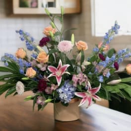 Mixed bouquet in a beige vase with pink lilies and peach roses