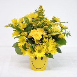 Yellow flowers arranged in a smiley-face pot