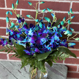 Blue and purple orchid bouquet in a clear glass vase