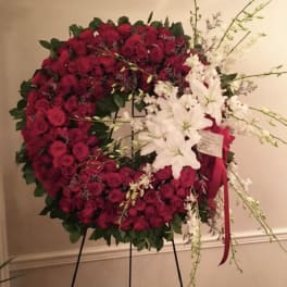 Large red rose wreath with white lilies on a stand