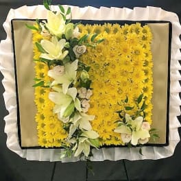 Yellow floral funeral spray with white lilies and roses