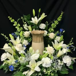 White lilies and roses arranged around a tall urn centerpiece