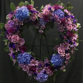 Heart-shaped floral wreath with blue hydrangeas, pink roses, and purple daisies