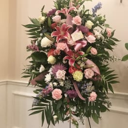 Standing floral spray with pink lilies, roses, and carnations on an easel